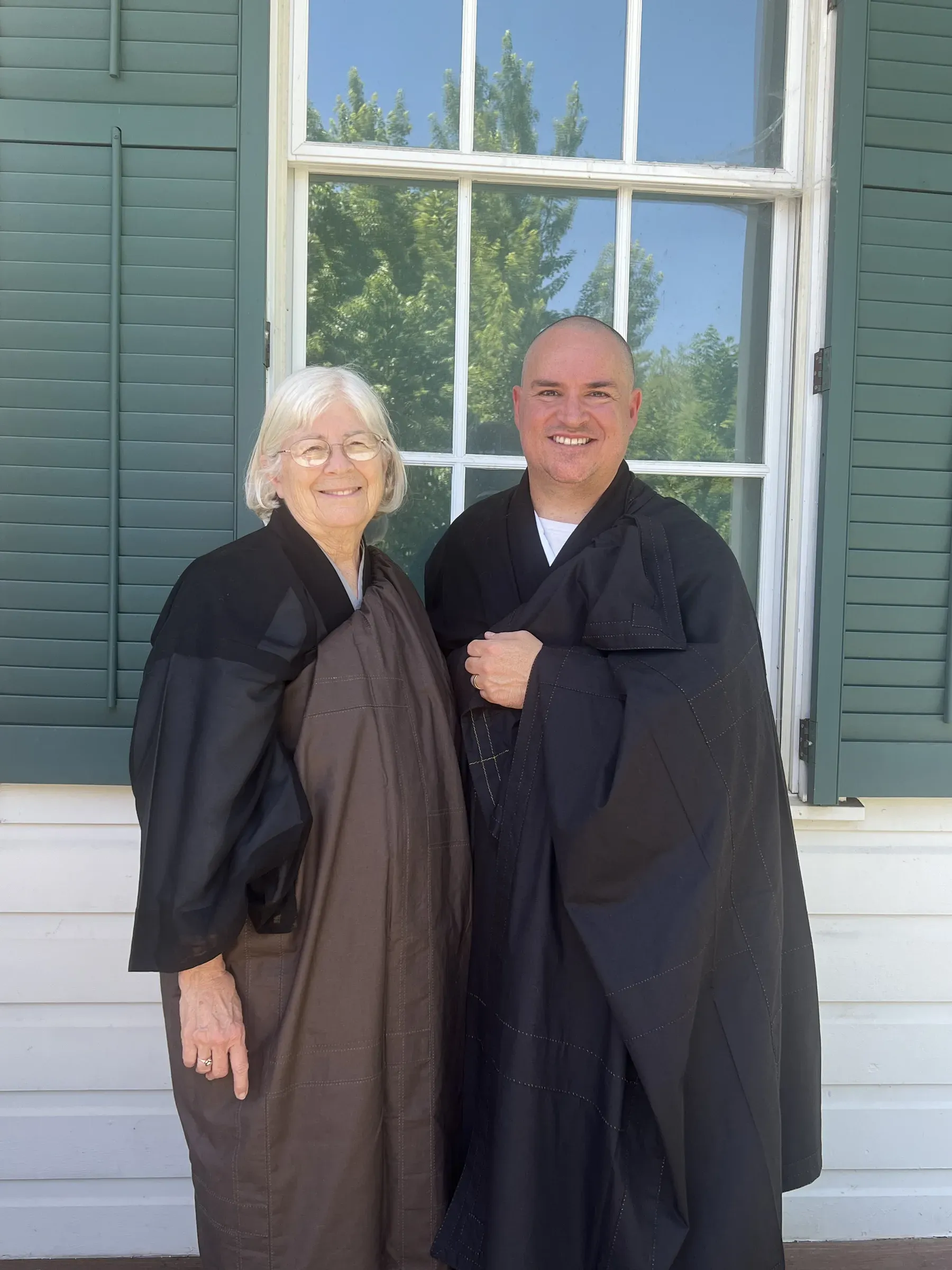Rev. Shinzan Sekibu Alice Tulloch and Sōbu Tetsuzan Jeff Urmston standing together outside after Jeff’s shukke tokudo ceremony, smiling at the camera.