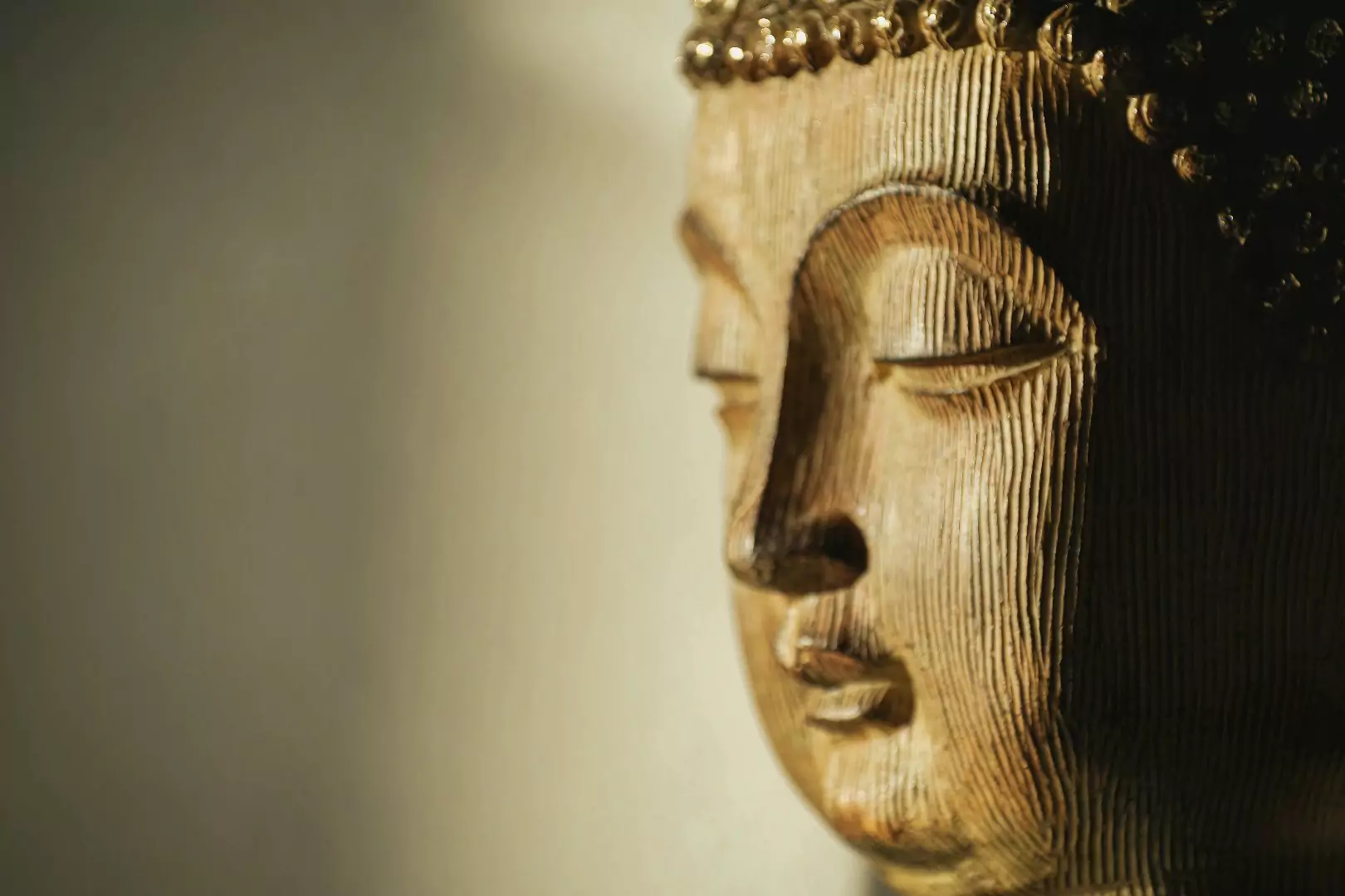 Photo of a carved Buddha face on a wooden panel.