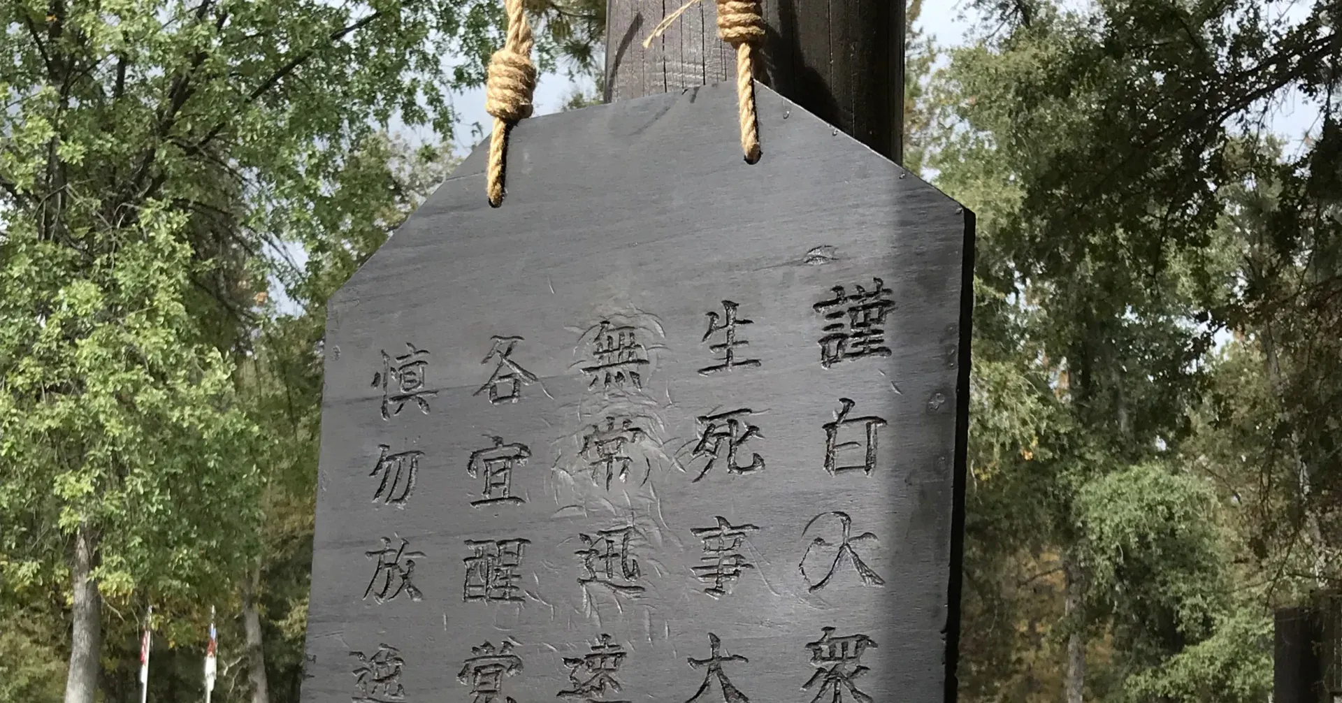 Photo of a hanging wooden panel with kanji characters carved into it and a mallet hung on the handle.